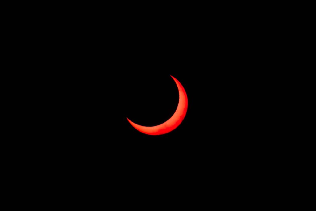 Stunning image of a red crescent moon during an eclipse against a black background.